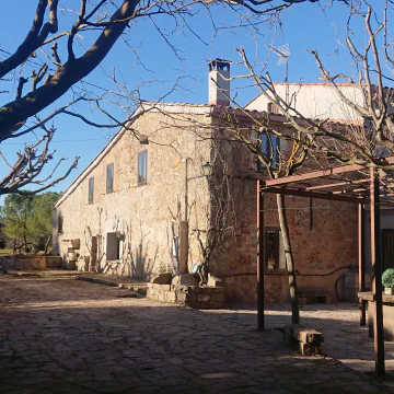 The stone facade of Cal Penedes seen from the courtyard on a clear winter afternoon